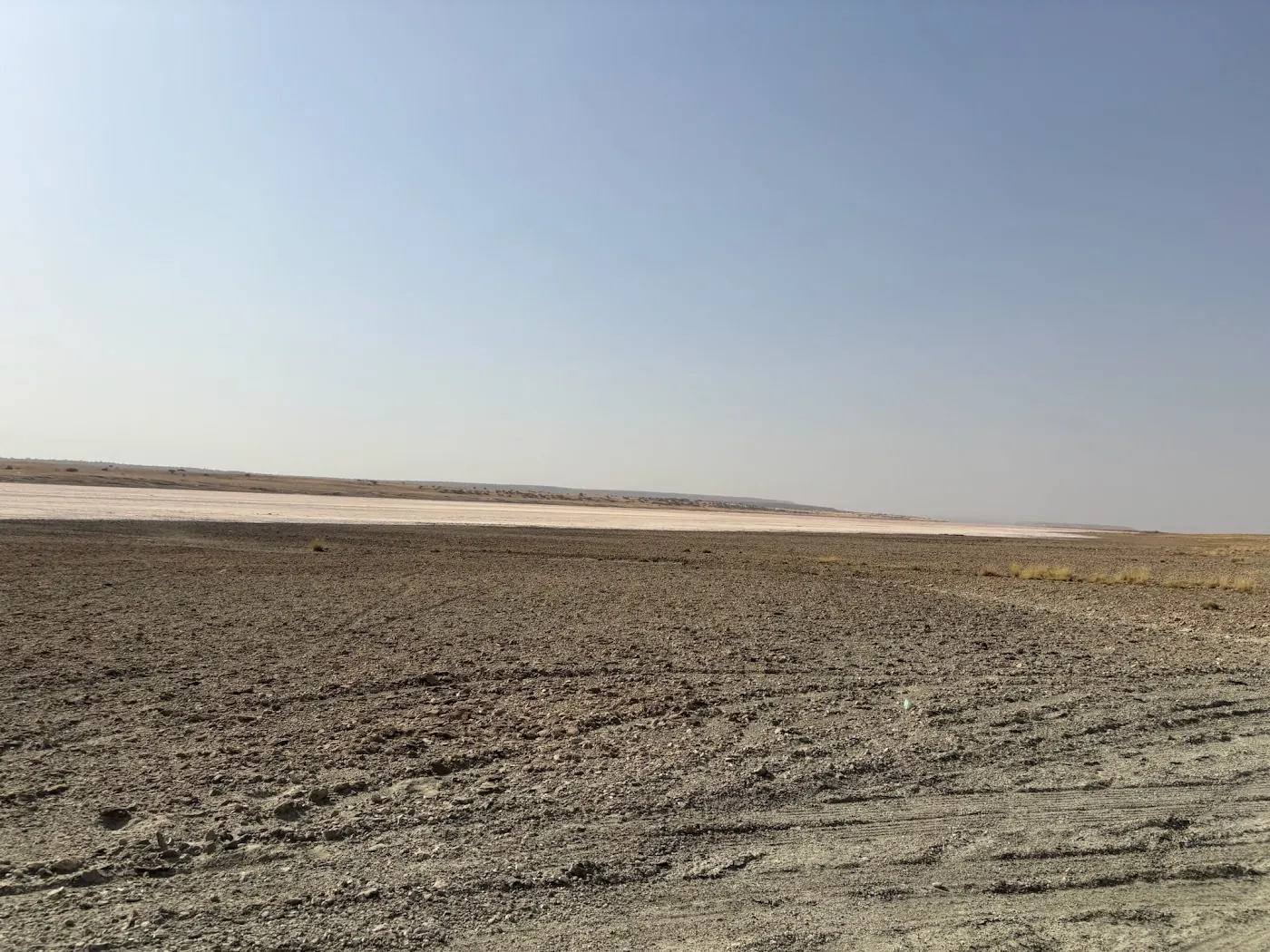 Cracked stony ground running out to a white salt flat