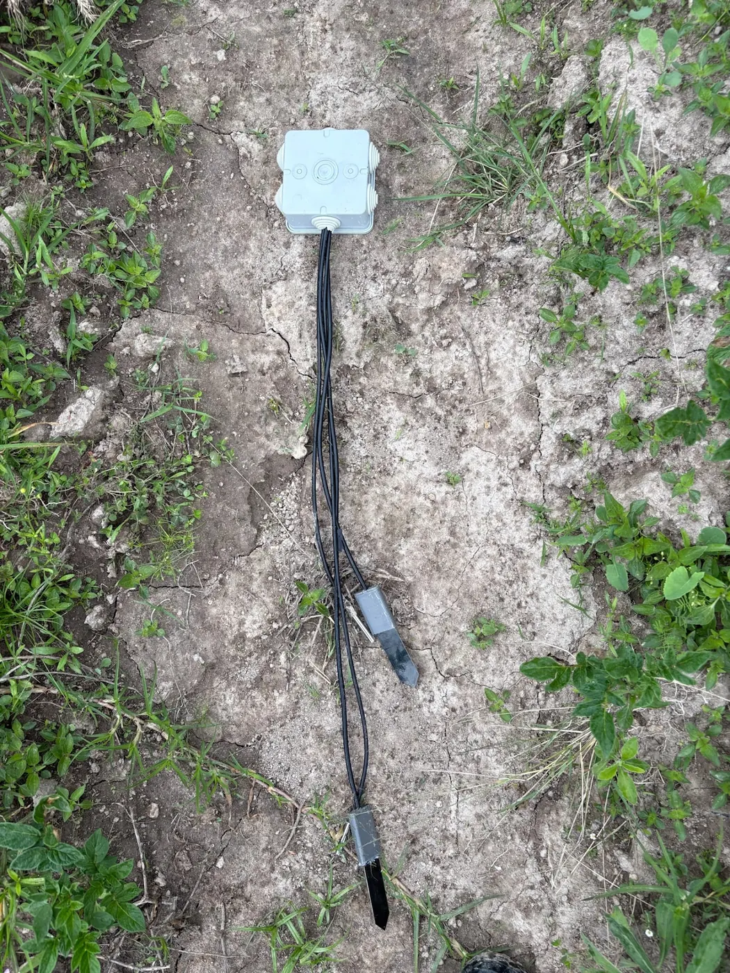 Two soil sensor probes and their housing on cracked ground
